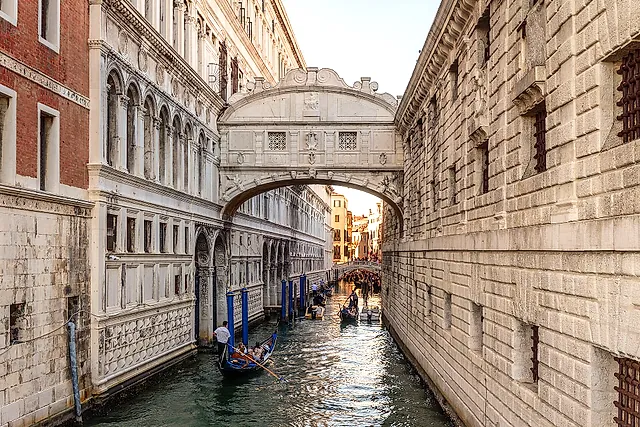 The white stone Bridge of Sighs crossing a canal between the Doge's Palace and the New Prisons, with a gondola below