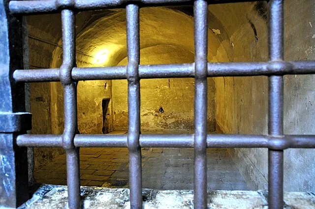 An iron-barred cell door in the prisons of the Doge's Palace, with a vaulted stone chamber behind it