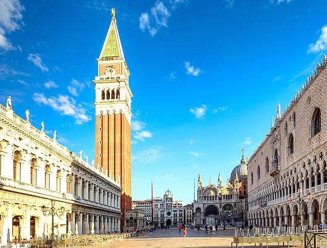 St Mark's Campanile rising above Piazza San Marco under a blue sky, with the Libreria Marciana and the Doge's Palace on either side