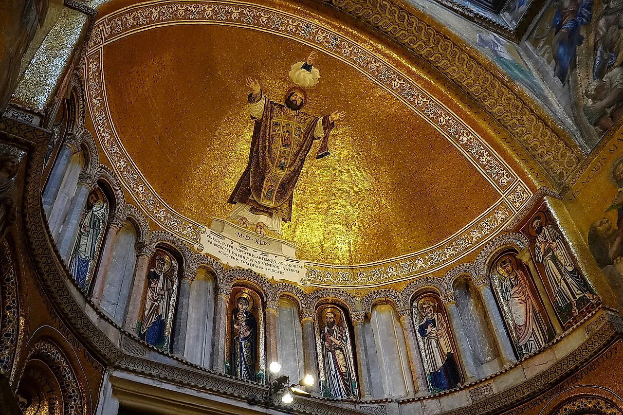 Golden mosaics in a semi-dome of St Mark's Basilica, with a large standing figure above rows of saints