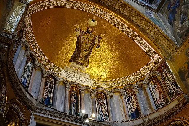 Golden mosaics in a semi-dome of St Mark's Basilica, with a large standing figure above rows of saints